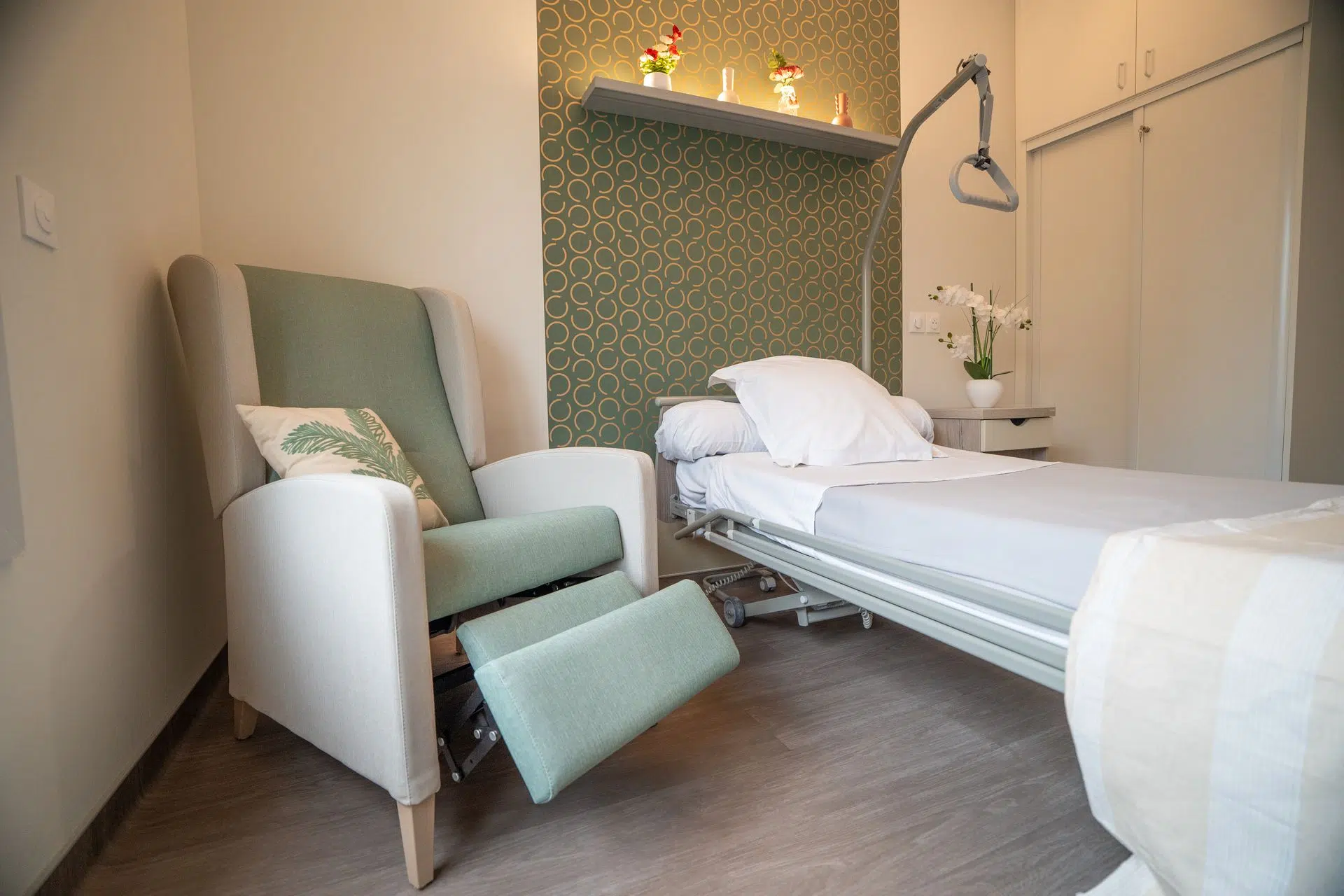 Fauteuil inclinable et lit médicalisé dans une chambre en EHPAD