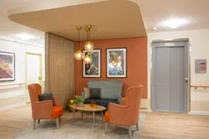 Ambiance résidentielle chaleureuse en EHPAD avec mobilier en bois clair et assises colorées