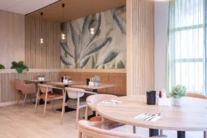 Salle de restaurant d’EHPAD avec tables et chaises à accoudoirs adaptées aux personnes âgées