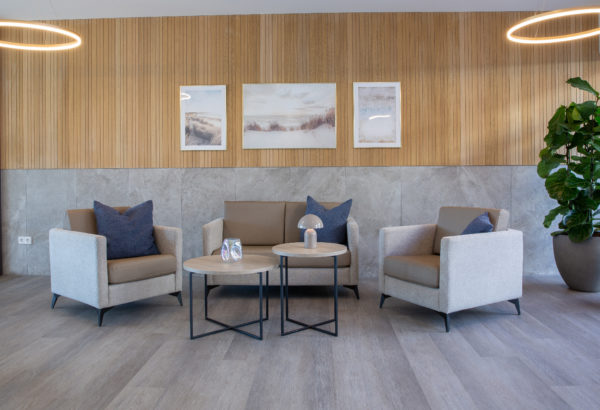 Salon lumineux d’EHPAD aménagé avec fauteuils, canapés et tables basses CARELINE