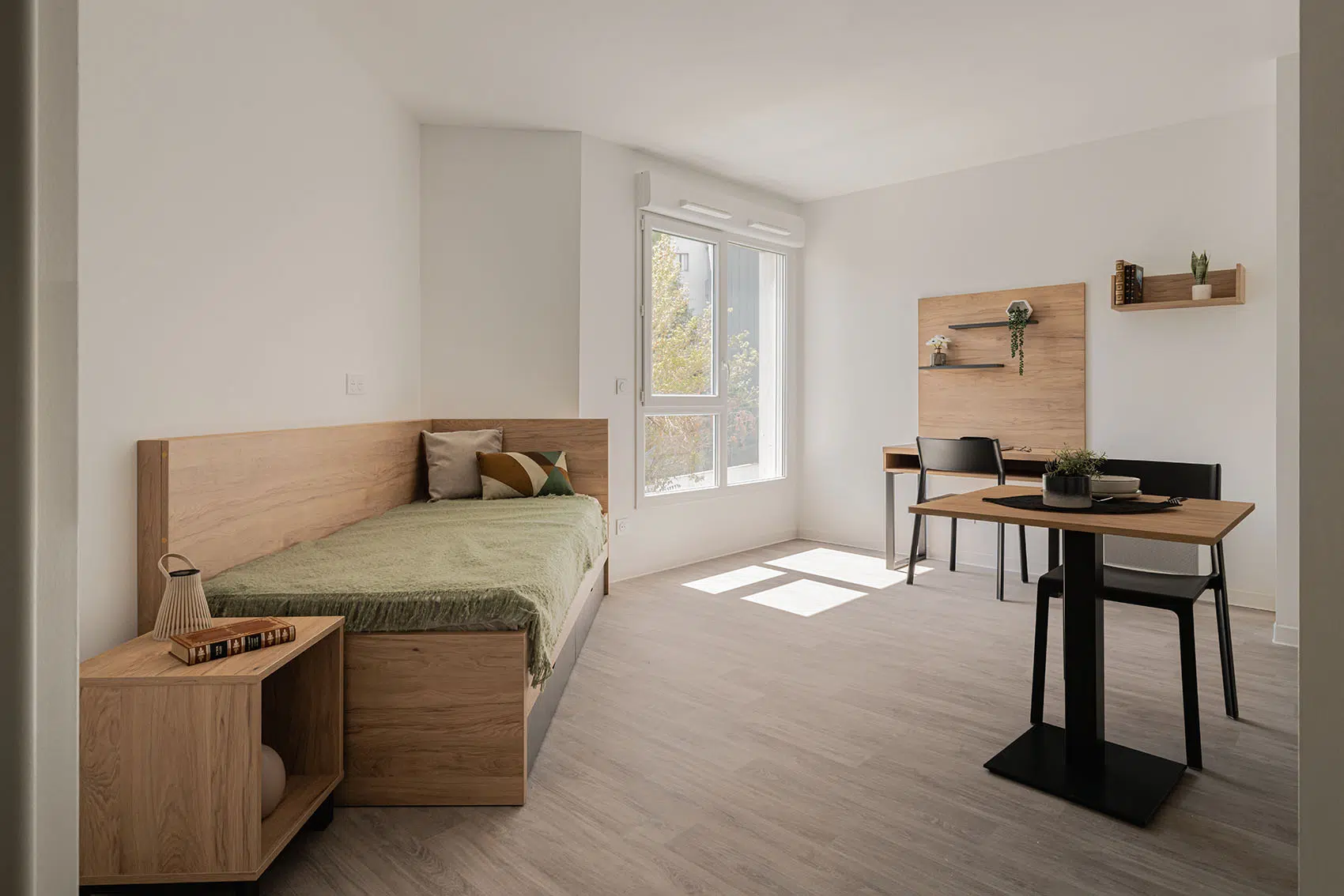 Logement étudiant aménagé par CARELINE avec lit simple, chevet, bureau sur mesure et table en finition bois.