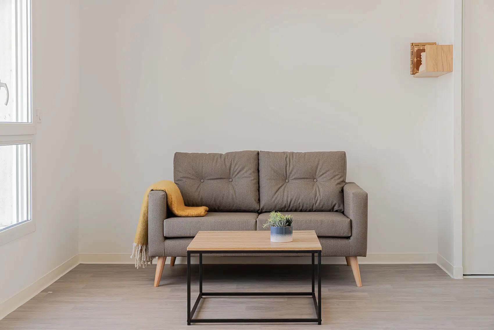 Coin salon avec canapé taupe deux places et table basse finition bois sur piètement noir, résidence Le Triangle.