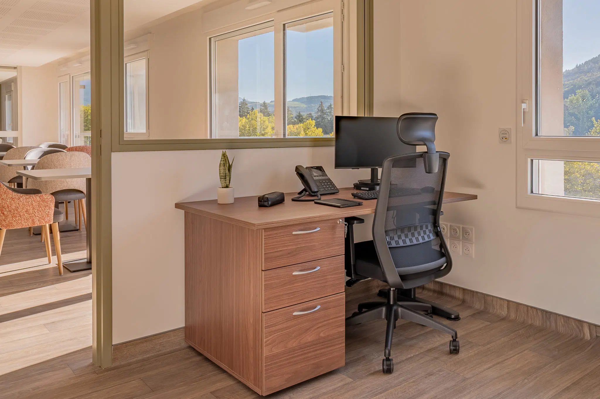Bureau en finition bois avec caisson de rangement et chaise de bureau dans la résidence Le Bocage.