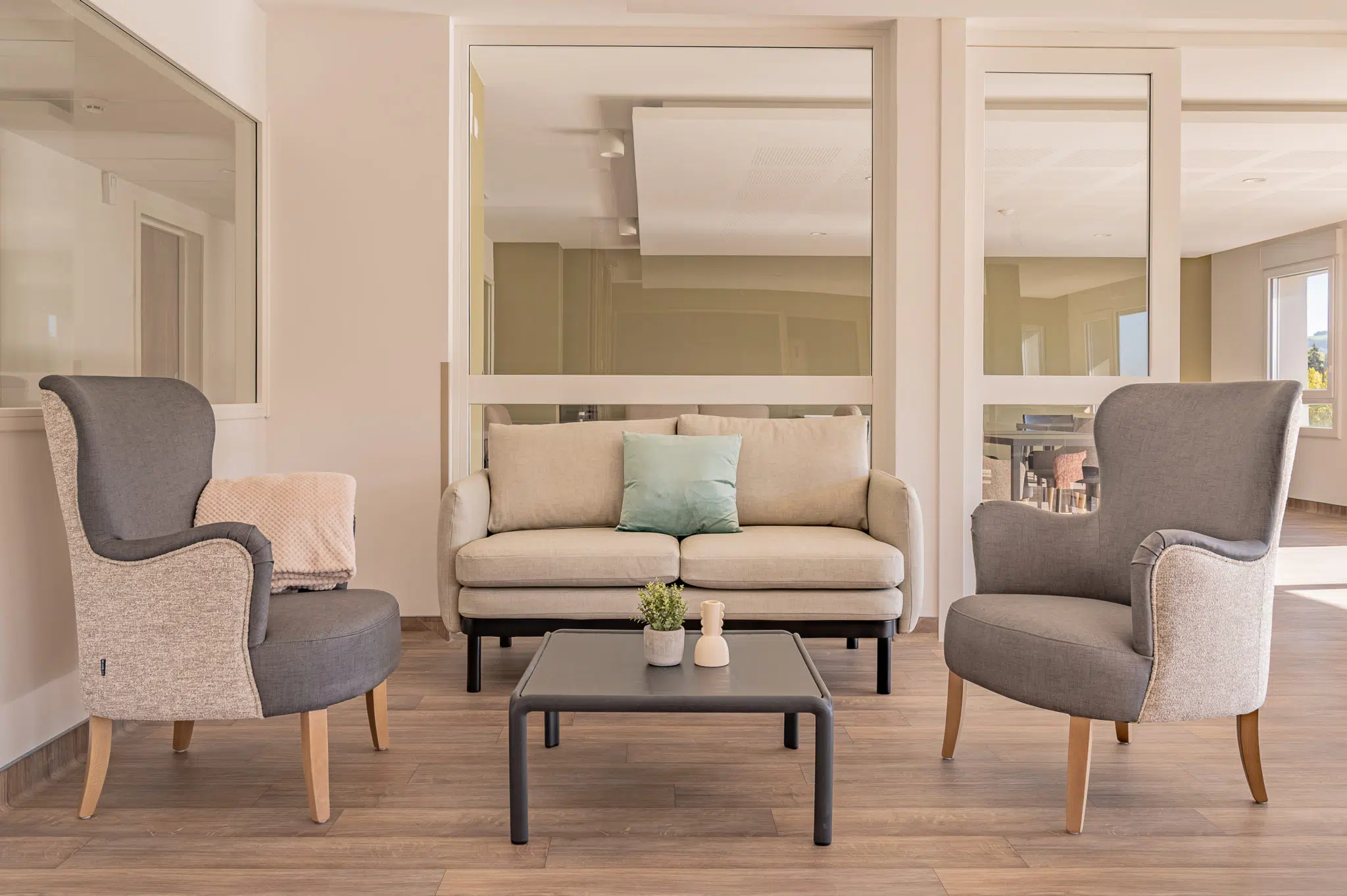 Canapé ORLEA, fauteuils SWING gris et table basse PALERME dans un salon.
