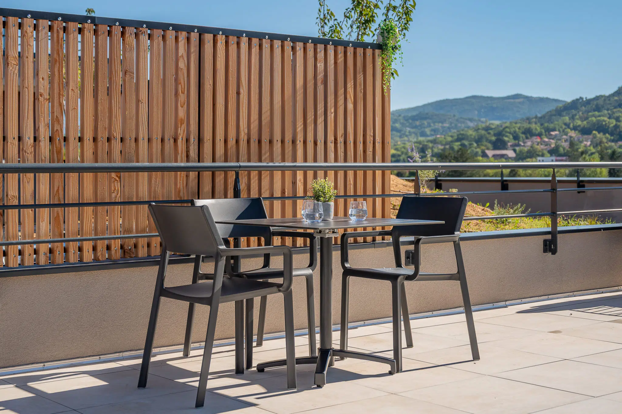 Table et chaises NAPLES sur la terrasse du Bocage à Gap, avec vue sur les montagnes.